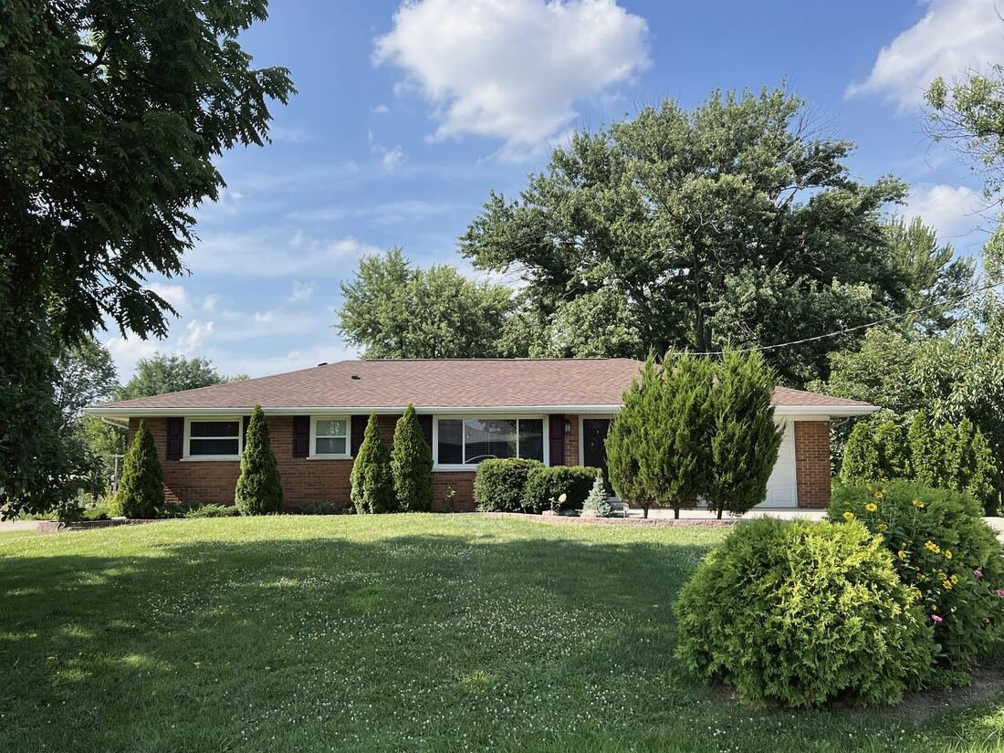 Brick ranch home with a new roof, green lawn and trees