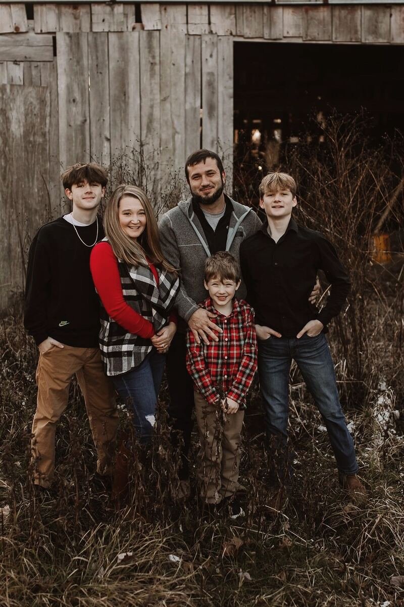 The Fee family, five people standing together outside in front of an old barn