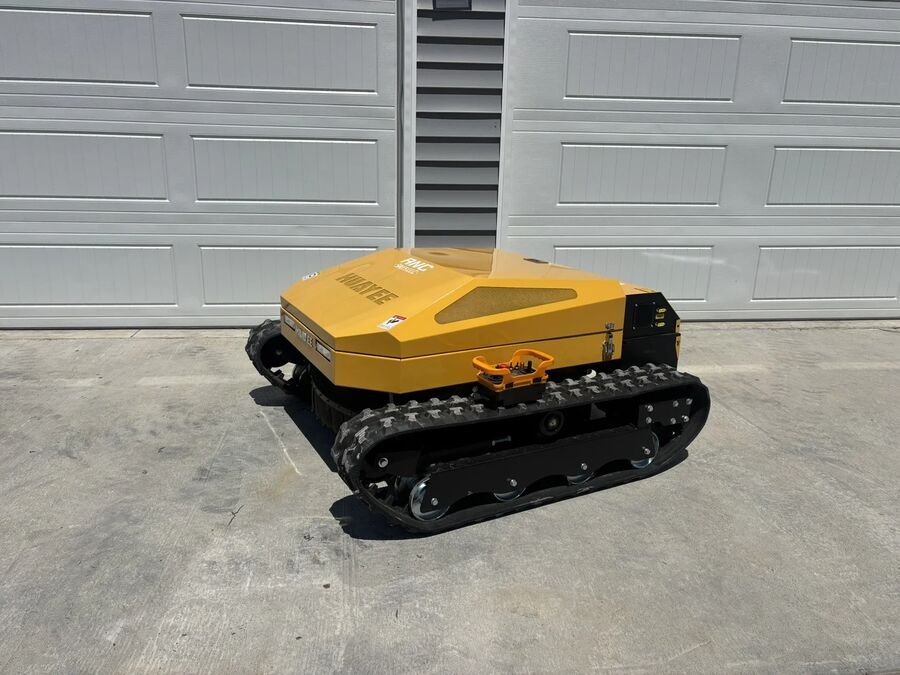 Orange and black tracked remote control mower with a low hood, in front of garage doors