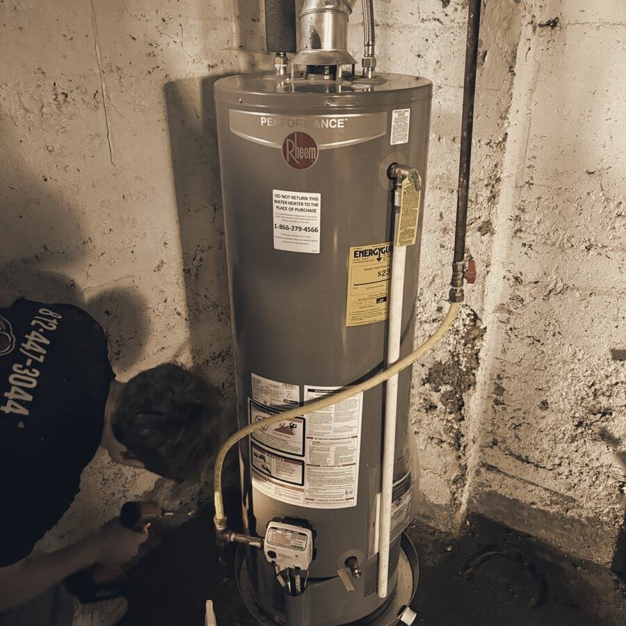 A Shipp's tech kneeling beside a water heater in a basement